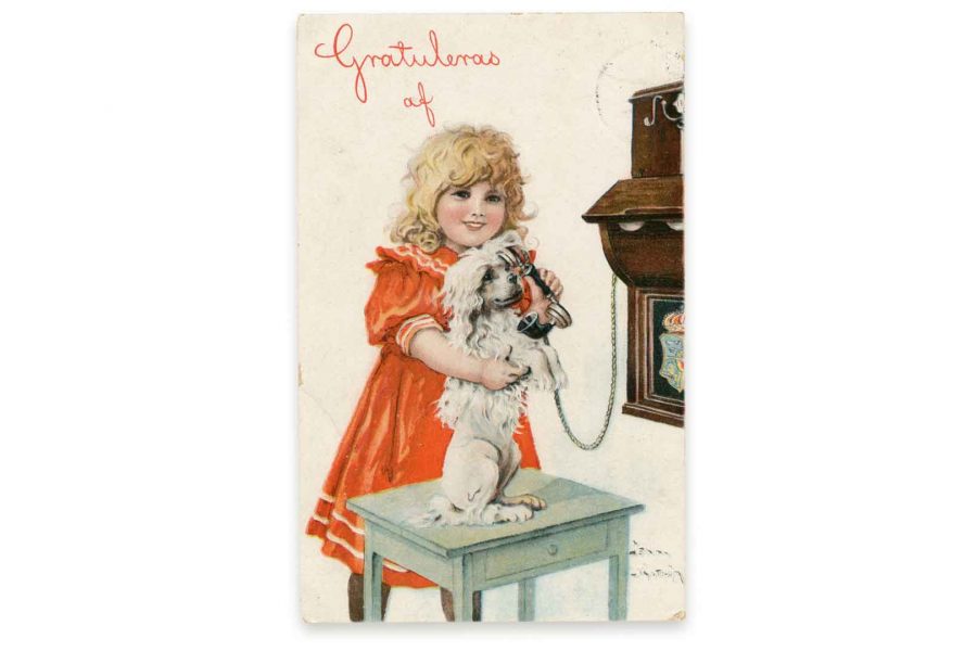 Ett barn i röd klänning står nära ett bord där en hund håller en telefonlur vid ett gammalt telefonbord. Texten "Gratuleras af" syns ovanför. Illustration av Jenny Nyström med en söt och lekfull stämning.