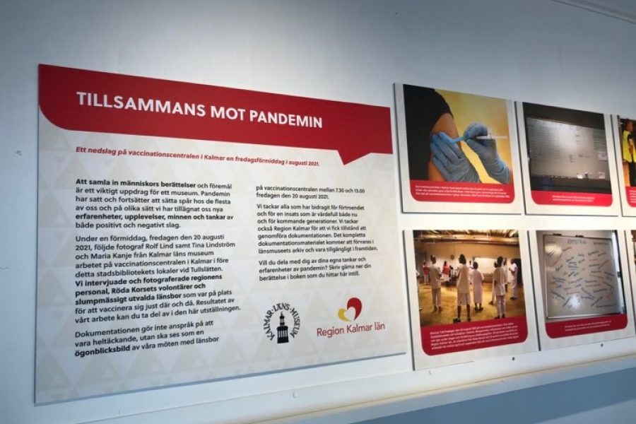 Informationspanel på en utställning visar text och bilder om pandemihantering i Kalmar län. Texten "Tillsammans mot pandemin" inleder. Bilder visar vaccinering och dokumentation av upplevelser. Logotyper från Kalmar län och Region Kalmar län syns.