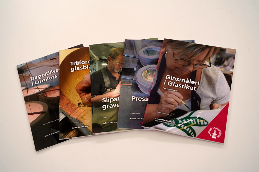Fem bokomslag ligger bredvid varandra. De visar olika aspekter av glasproduktion: "Degeltillverkning i Orrefors", "Träformar för glasblåsning", "Slipade och graverade", "Pressglas" och "Glasmåleri i Glasriket". En man och en kvinna utför hantverk.